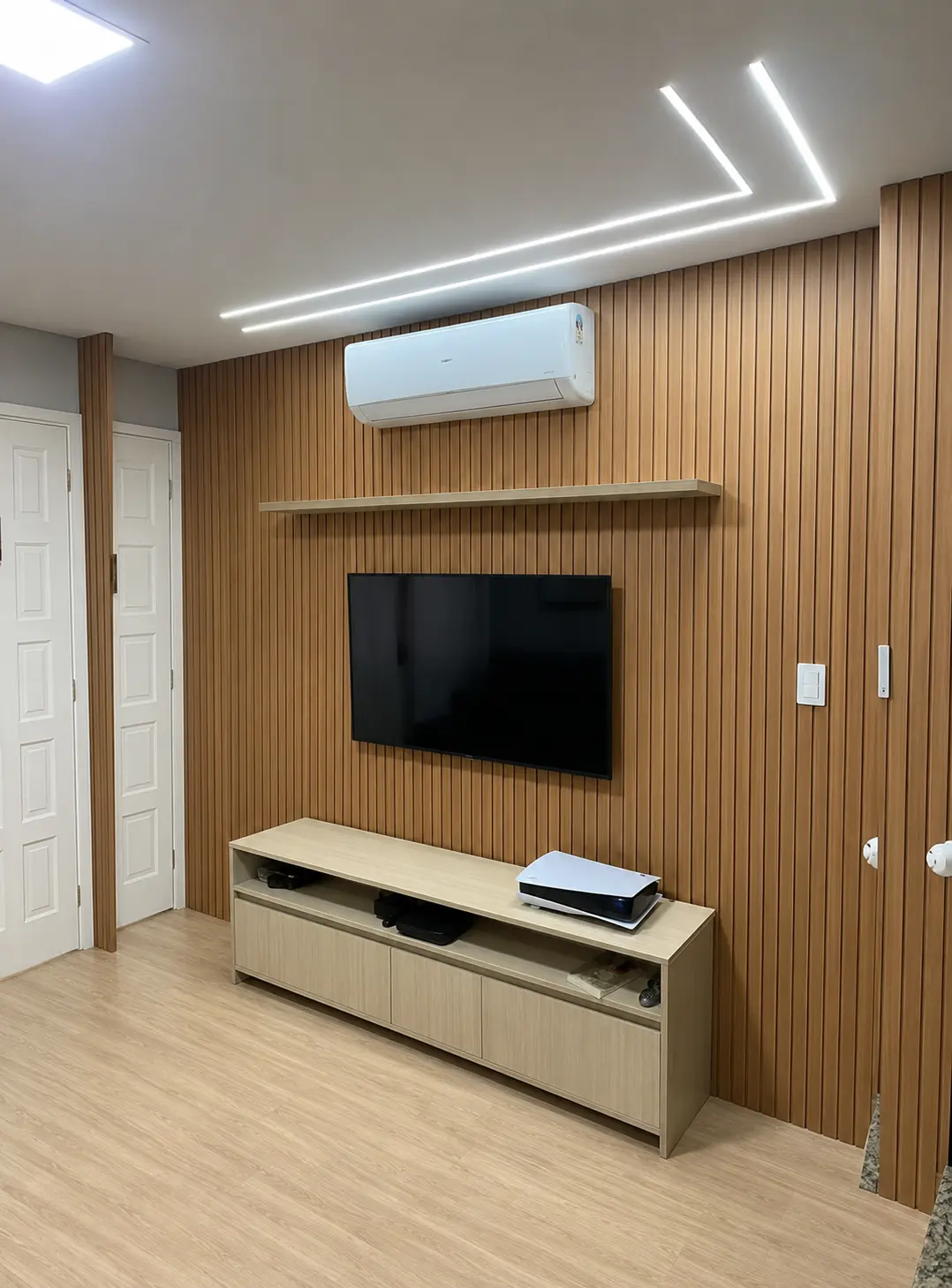 Sala com painel de televisão e rack planejados em madeira clara
